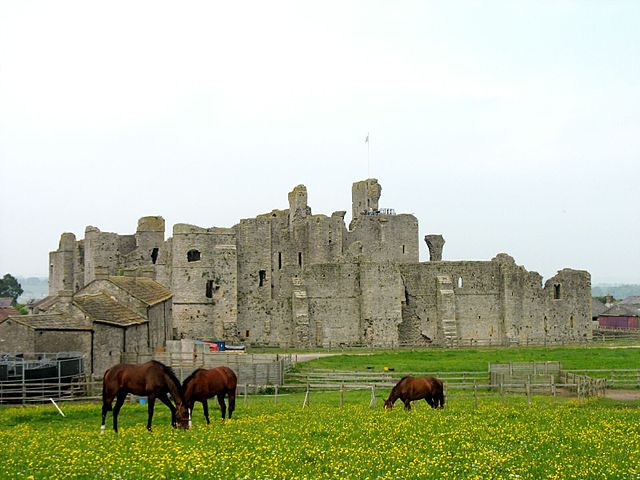 A large castle, with horses grazing in the foreground