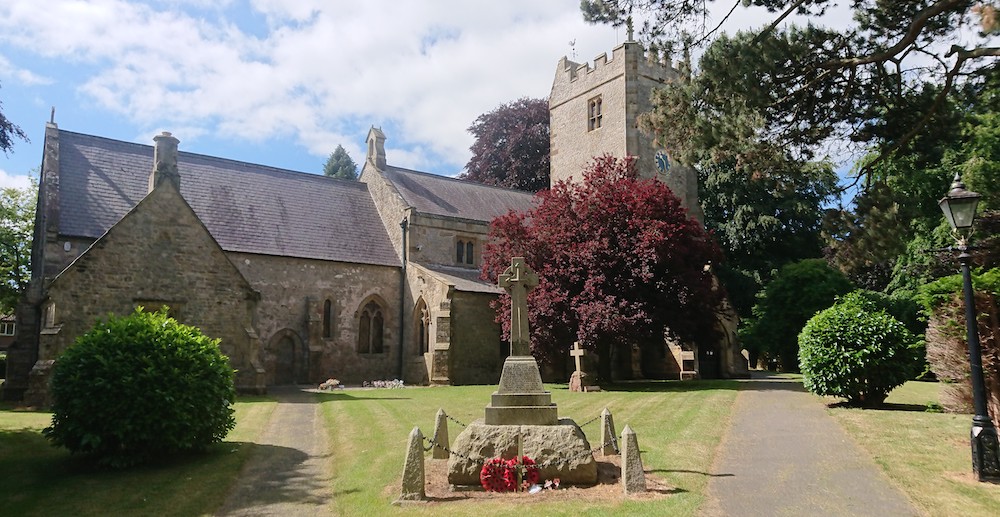 A church and leafy churchyard in sunshine