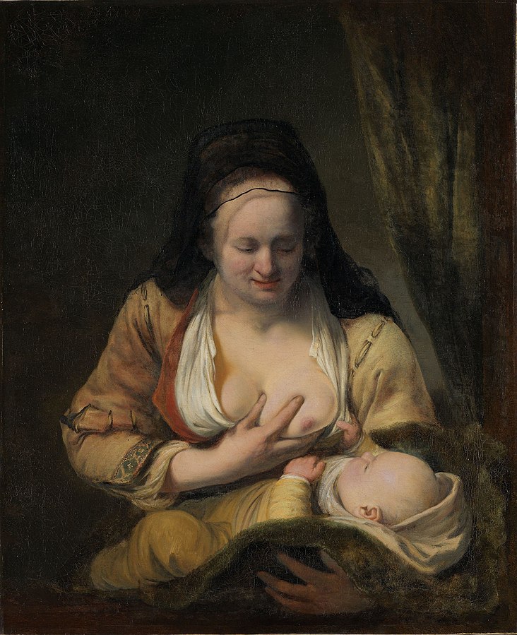 A woman with her breasts exposed holds an small baby, about to suckle it