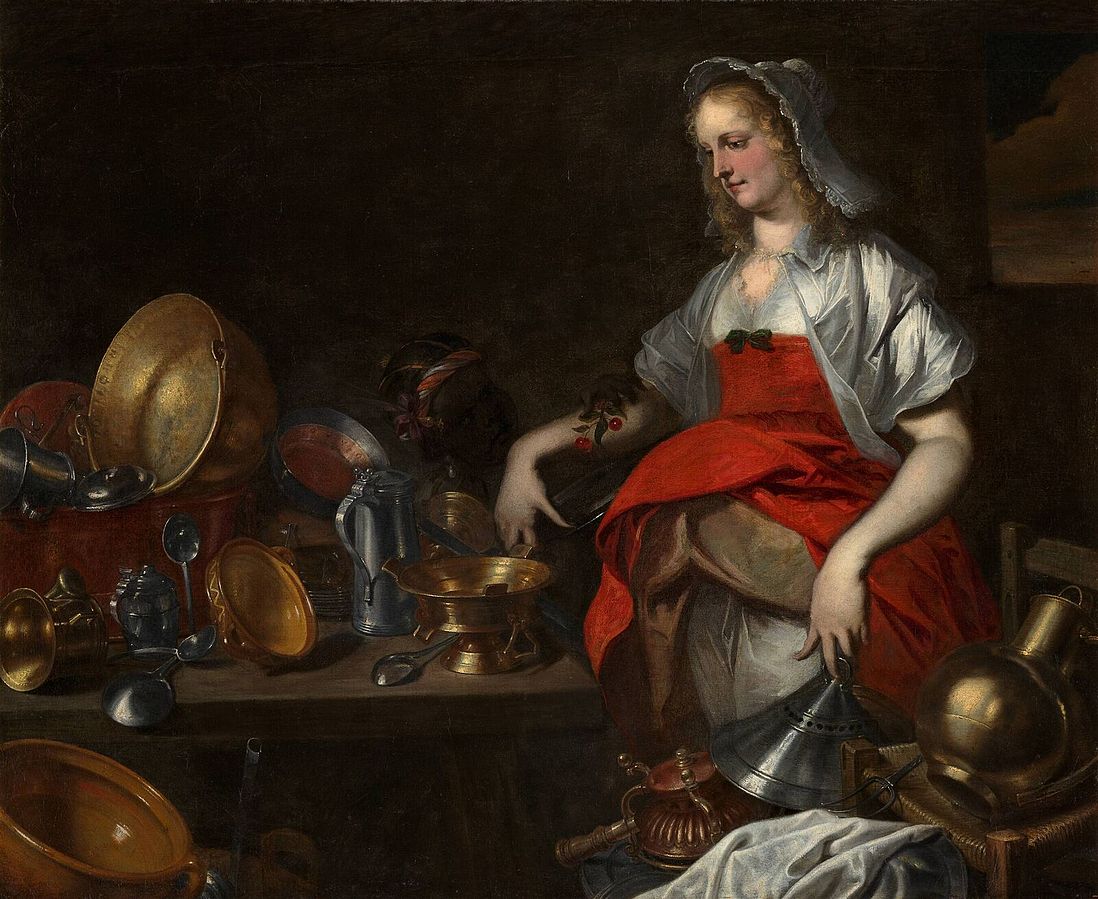 A well-dressed and perhaps pregnant young woman stands next to a table which holds a variety of metal jugs and plates